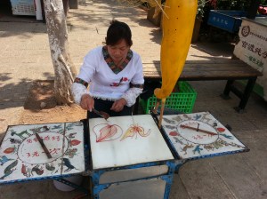 The lady is painting in sugar, which you can buy and then eat. Just awesome!